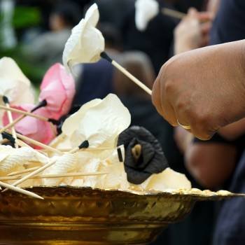 Hand of people picks up the paper flower from the tray during funeral in Buddhism temple