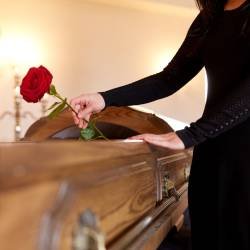 woman with red roses and coffin at funeral